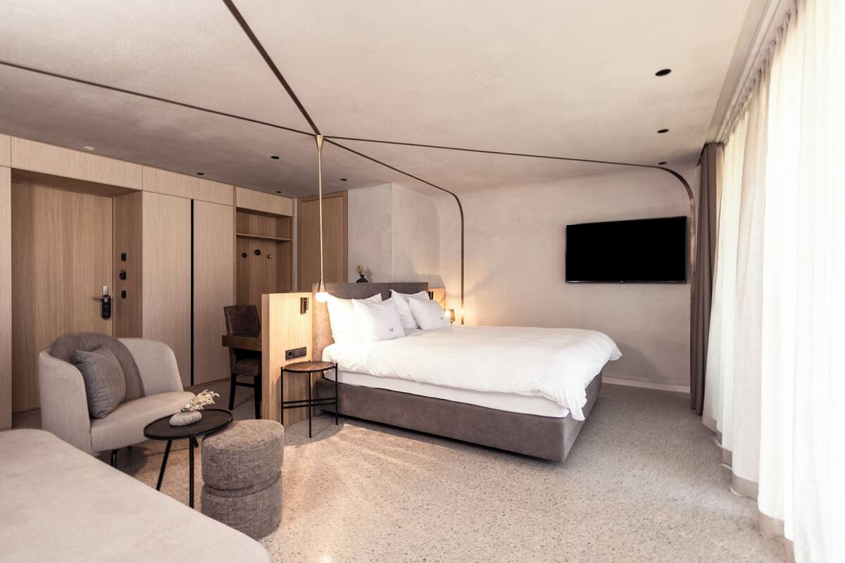 Une chambre moderne avec un lit, une chaise, une petite table et une armoire.
