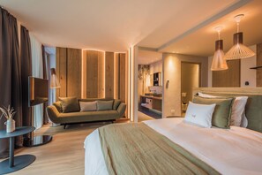 Una habitación de hotel moderna con una cama grande, un sofá, un televisor y una pared de acento de madera.