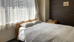 A hotel room with a bed, a nightstand, a telephone, and a window with sheer curtains. - Hotel Shin Osaka (Osaka)