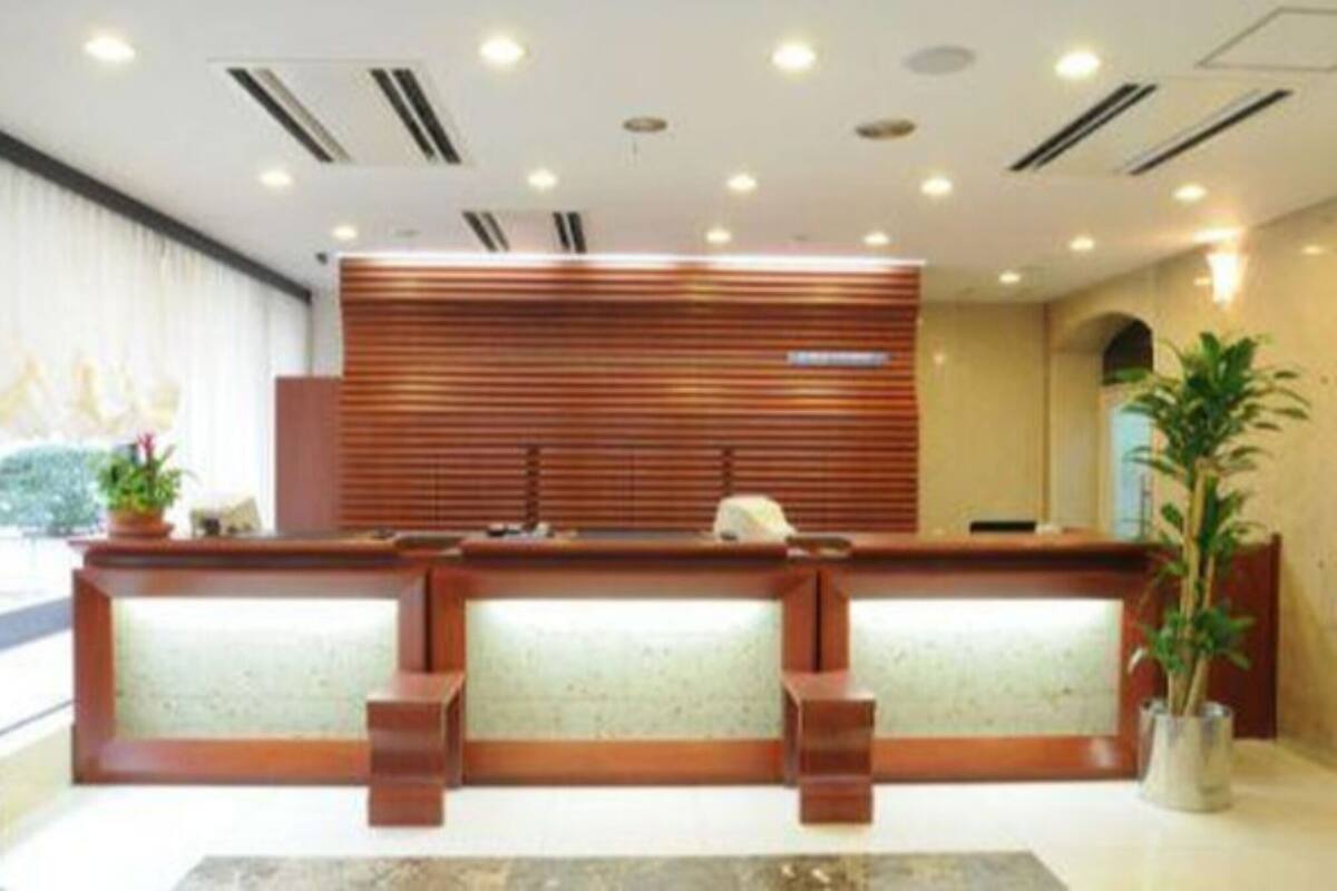A reception desk with a wooden finish and a glass partition.