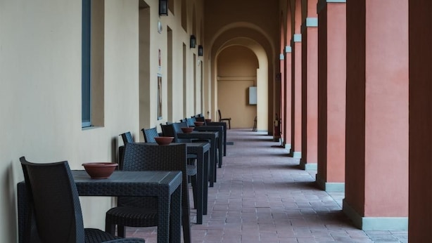 A corridor with rows of tables and chairs, each with a bowl. - Casale La Sterpaia (San Giuliano Terme)