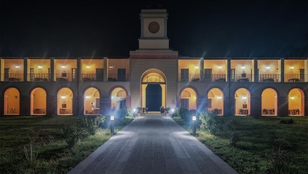 Un hotel con una entrada central en arco, varios balcones y una torre del reloj.