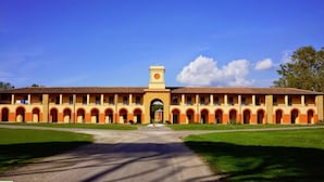 A large building with a central archway and a clock tower. - Casale La Sterpaia (San Giuliano Terme)