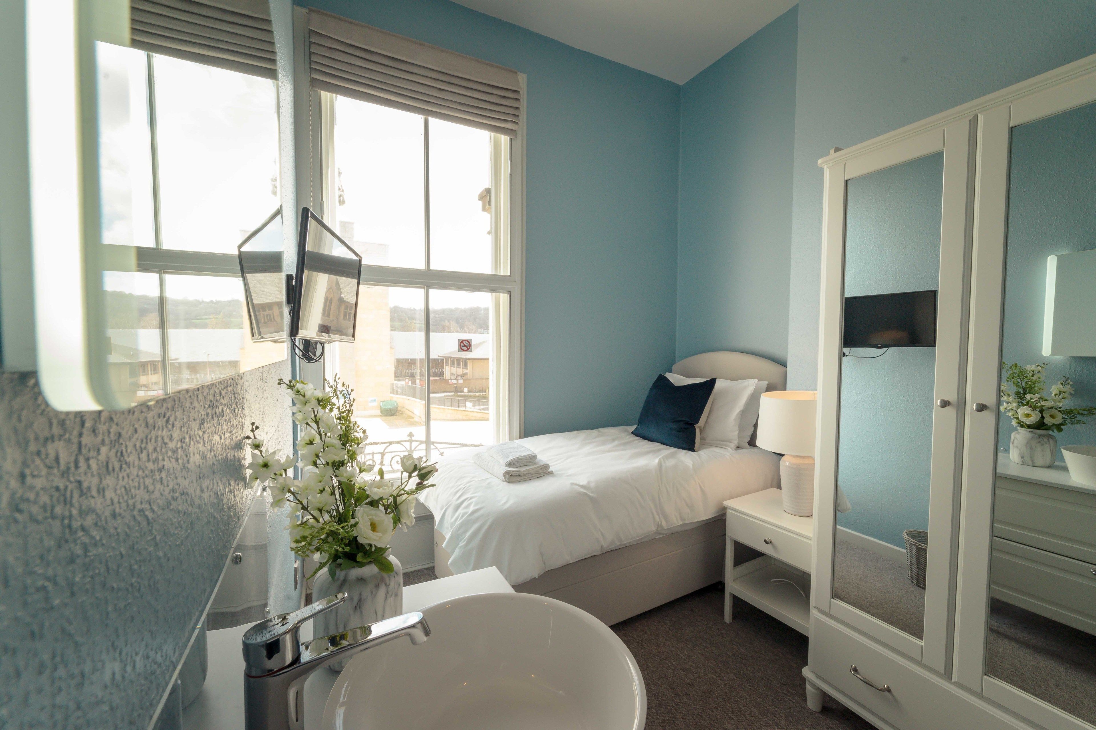 A bedroom with a bed, bedside table, and a large mirror.