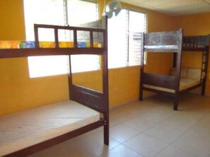 A room with two bunk beds, a window with blinds, and a ceiling fan.