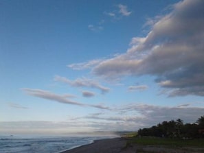 A beach with a clear sky and scattered clouds.