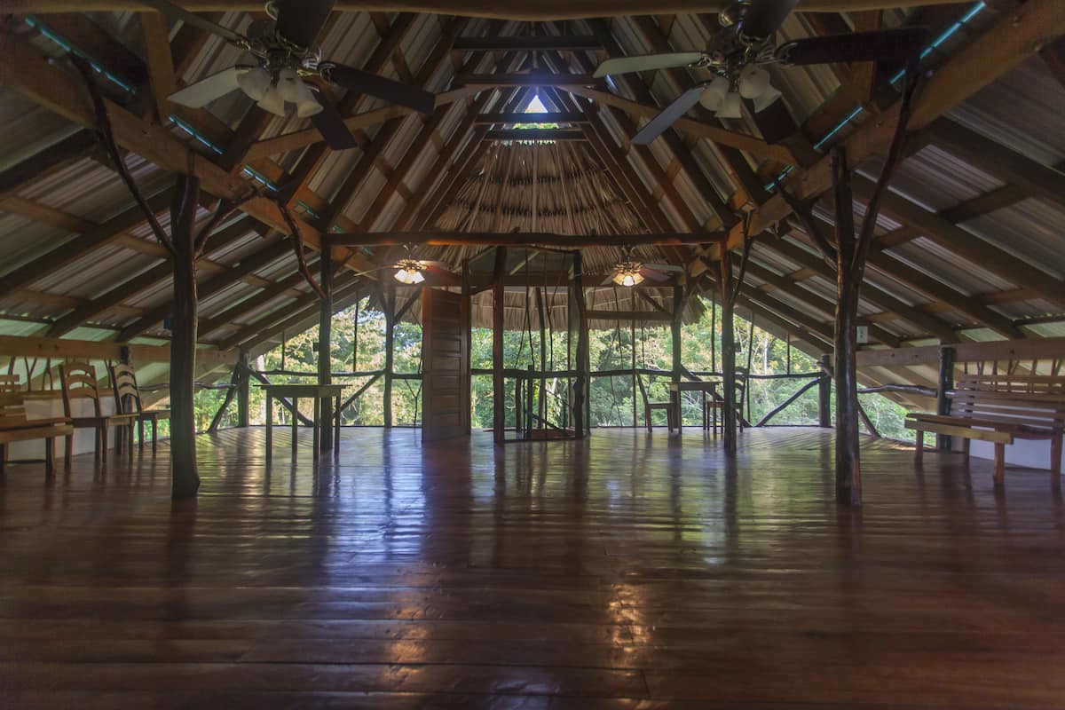 A spacious wooden pavilion with a high ceiling and natural light from large windows.