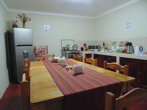 A compact kitchen with a dining table, chairs, a refrigerator, a stove, and various kitchen appliances. - Magic Cusco (Cusco)