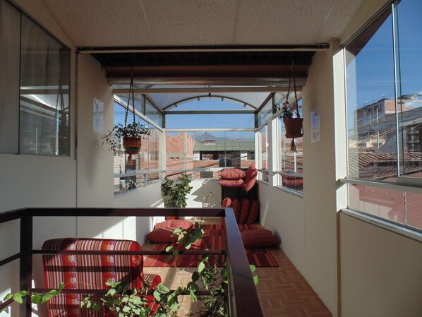 A balcony with a view of buildings, a striped sofa, and hanging plants. - Magic Cusco (Cusco)