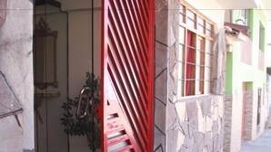 A doorway with a red metal gate, a potted plant, and a stone wall. - Magic Cusco (Cusco)