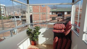 A balcony with a red patterned floor, a potted plant, and striped cushions. - Magic Cusco (Cusco)