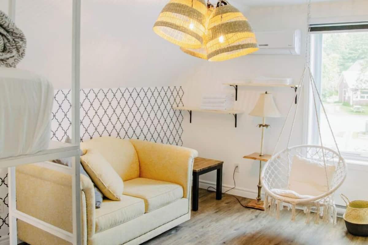 A modern living room with a sofa, hanging chair, and a large window.