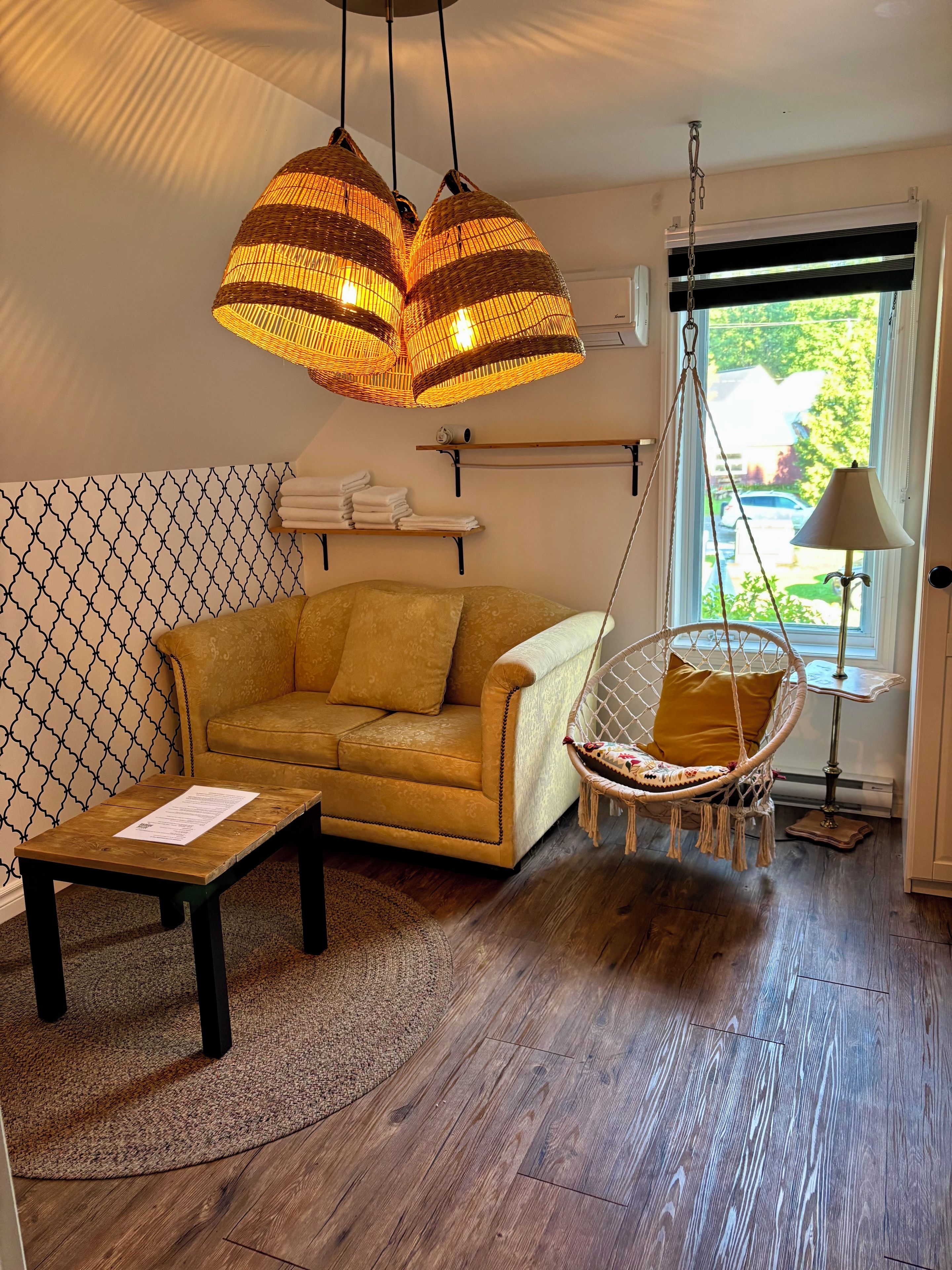 Una habitación con sofá, sillón colgante, mesa y ventana con vistas.