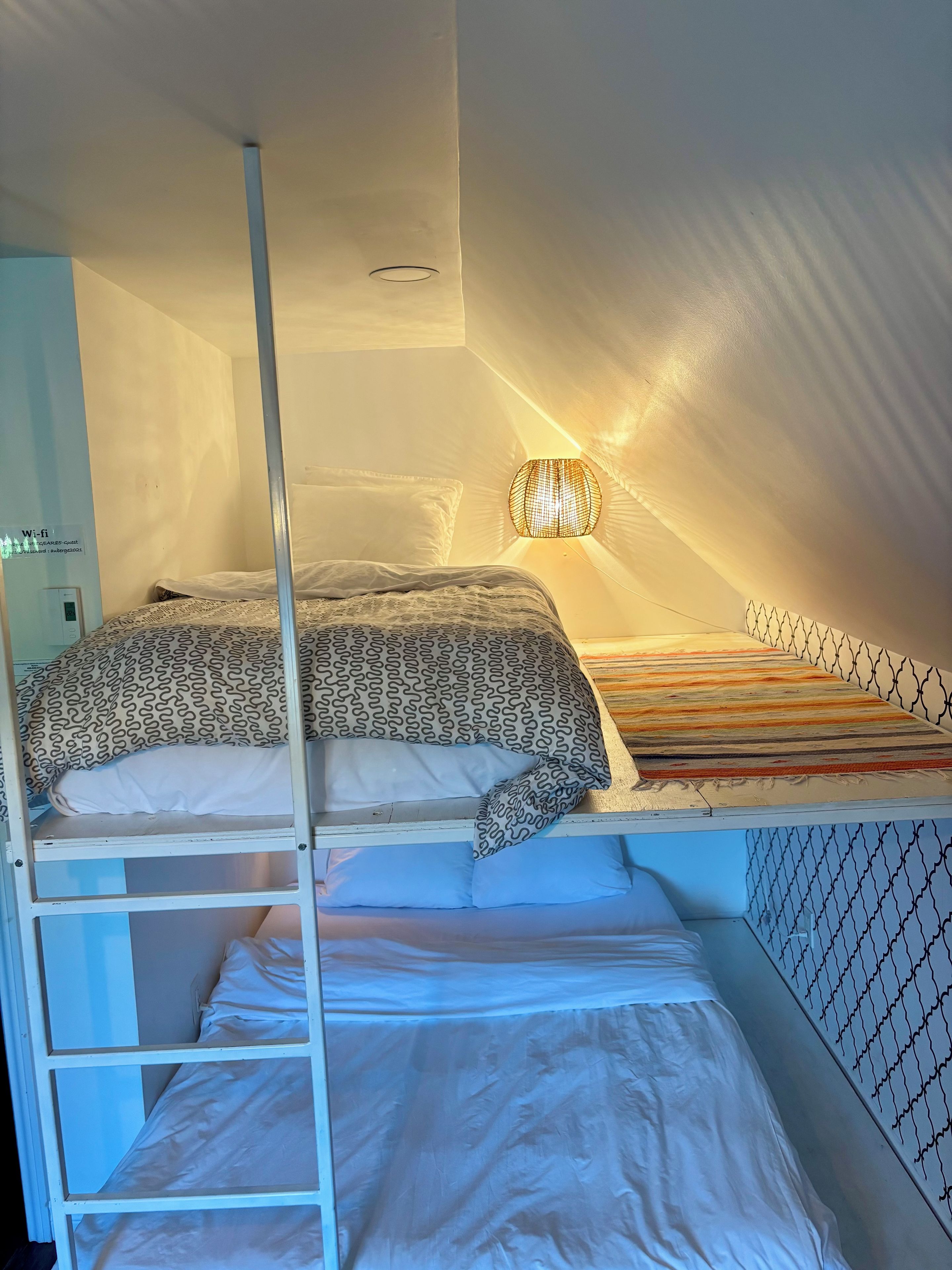 A bunk bed with a ladder, a wall-mounted light fixture, and a Wi-Fi sign.