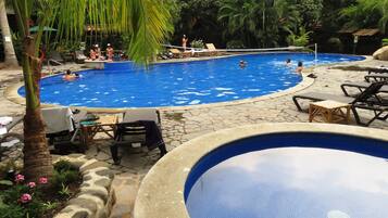 Alberca al aire libre, sombrillas en la alberca y camastros