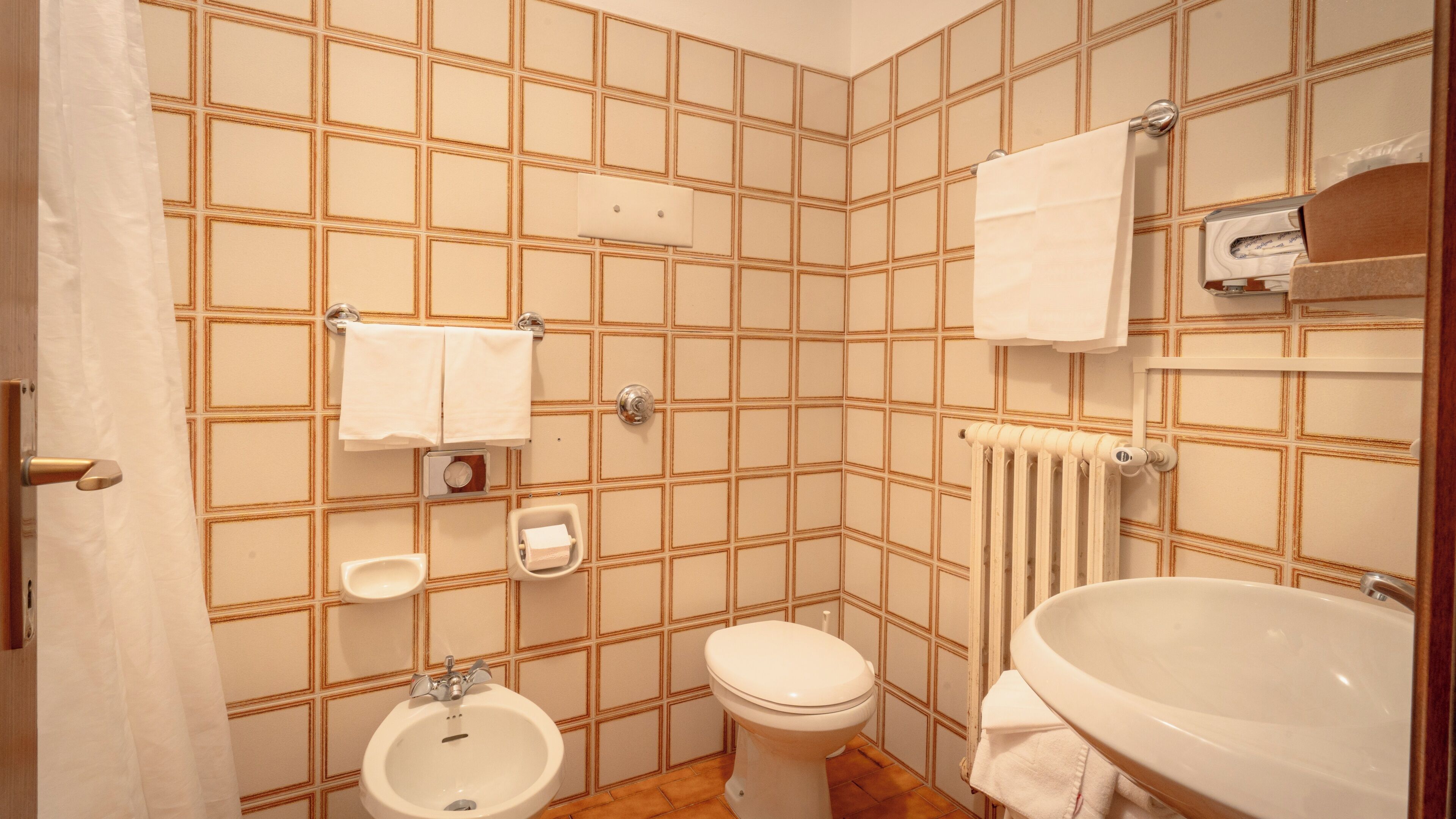 Un bagno con toilette, bidet, lavandino e porta asciugamani.