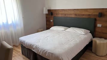 Ein ordentlich bezogenes Bett in einem Zimmer mit Holzboden, ein Kopfteil mit Holzpaneelen und eine Lampe auf dem Nachttisch.