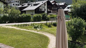 Blick auf Berge mit traditionellen Chalets, einer grünen Wiese und einer Holzterrasse.