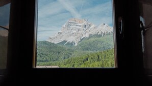 Bergblick durch ein Fenster mit Holzrahmen.