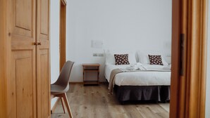 Ein Schlafzimmer mit Bett, Nachttisch, Stuhl und Holzschrank.