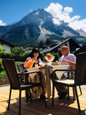 Dos personas cenando en una mesa al aire libre con vista a la montaña.