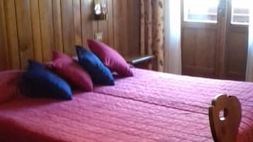 Een slaapkamer met een houten hoofdeinde, een bed met een roze deken en een houten stoel.
