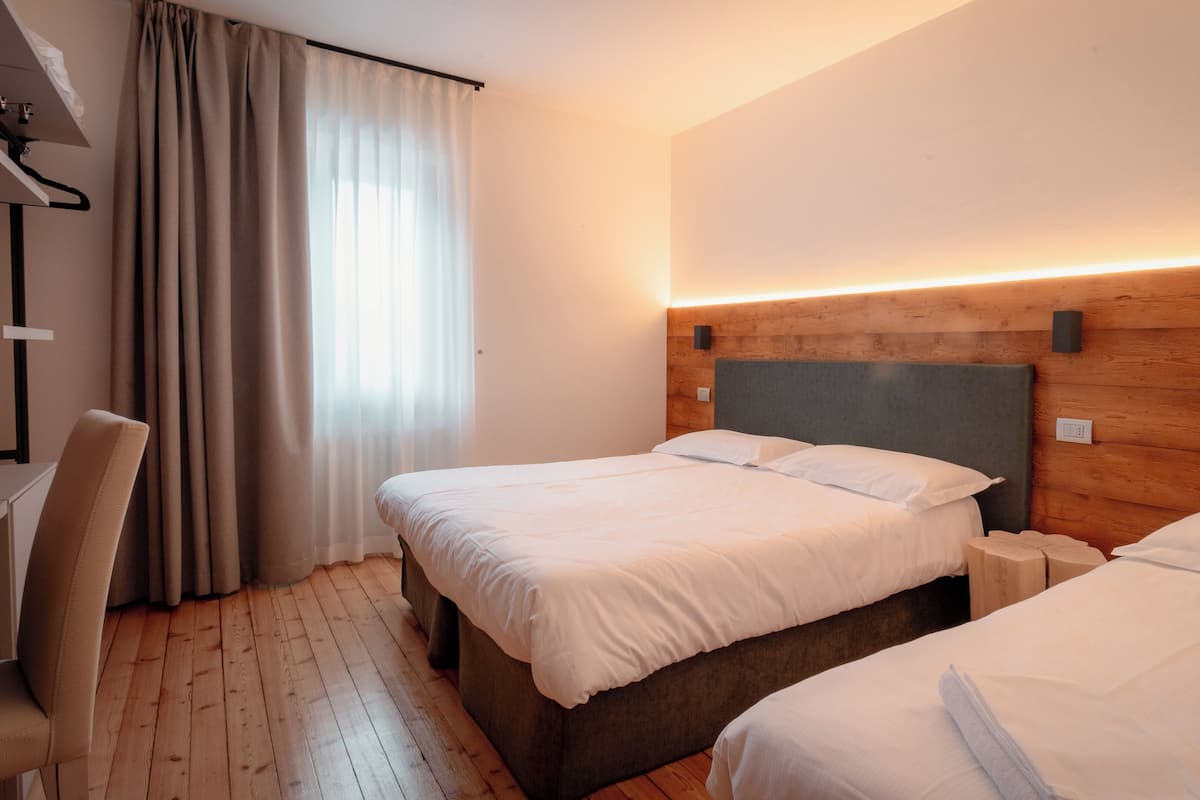 Habitació d'hotel amb dos llits, un capçal de fusta, escriptori i una cadira.