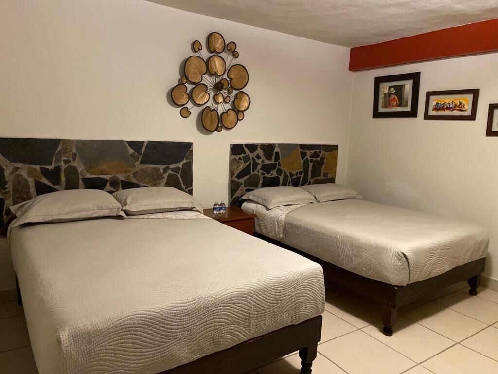 Um quarto com duas camas, decoração de parede em pedra e quadros emoldurados.