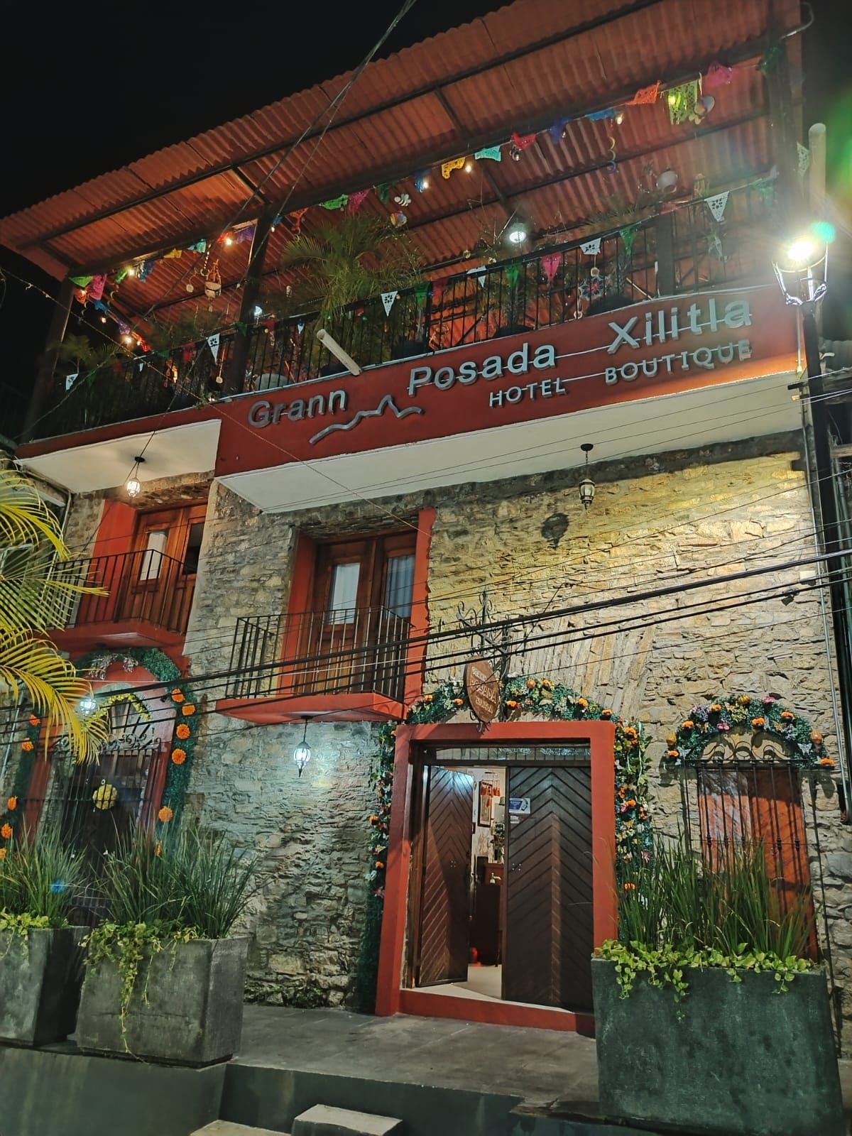 Ein Hotel namens 'Grann Posada' mit einem Balkon, verziert mit bunten Flaggen und Pflanzen.