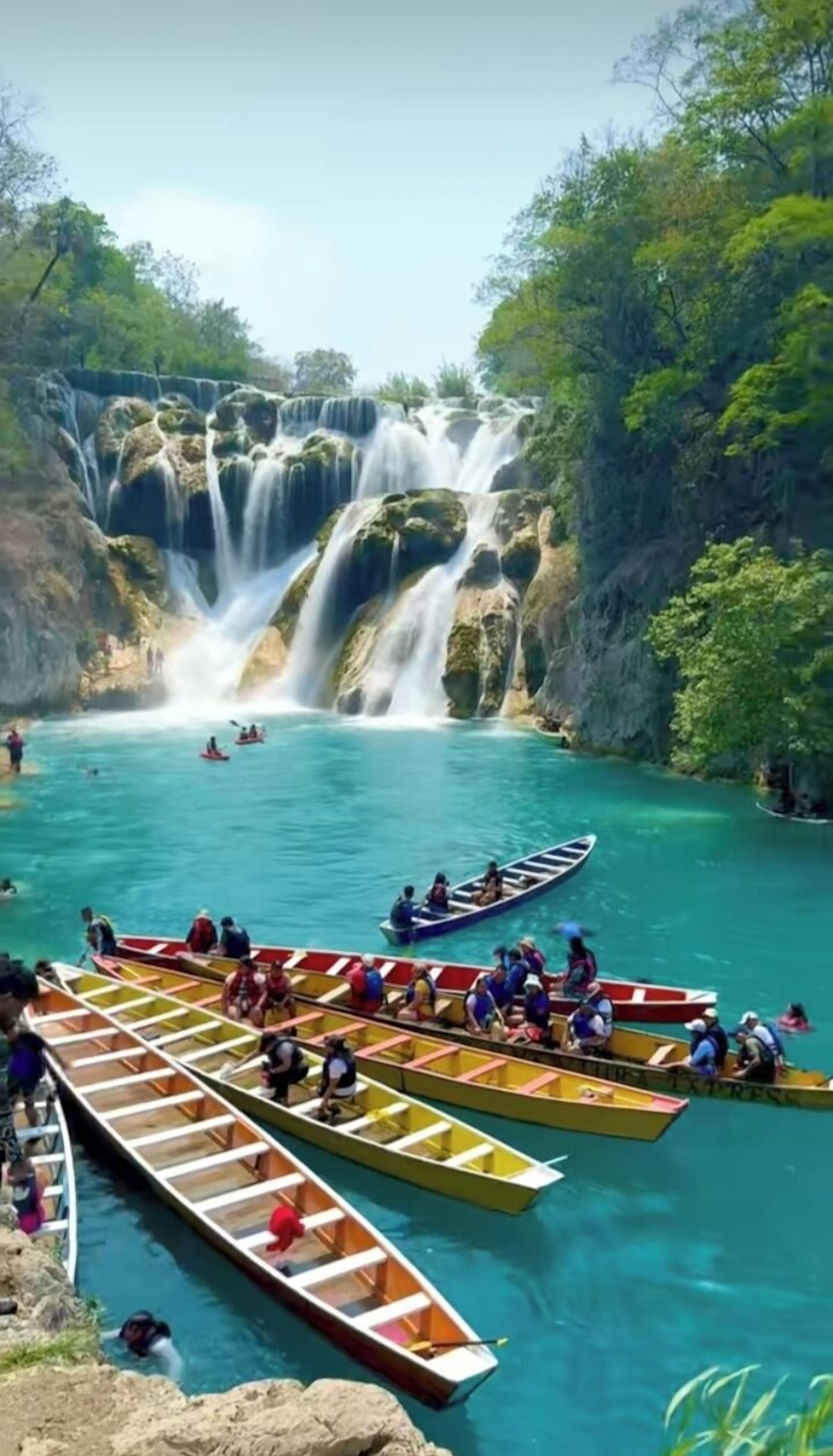 A waterfall with several boats in the foreground.