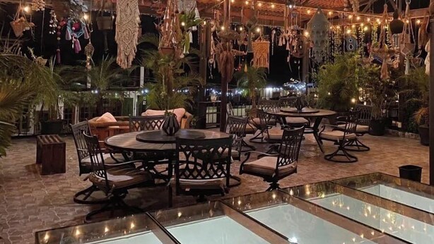 An outdoor dining area with round tables and chairs, surrounded by hanging decorations and string lights. - Grann Posada Xilitla (Xilitla)