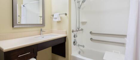 Un baño con lavamanos, espejo, toallero y bañera con ducha.