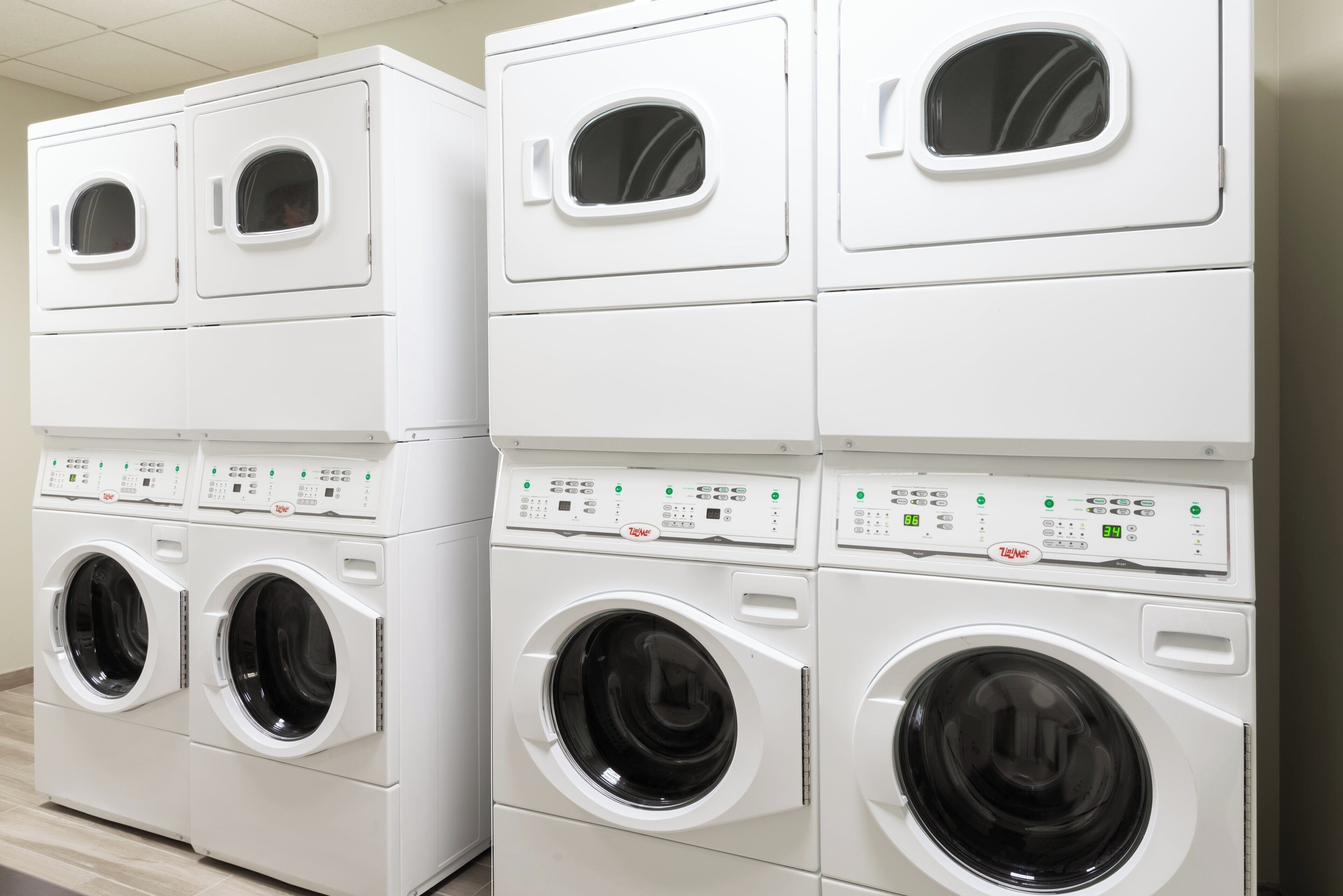 A row of stacked front-loading washing machines in a commercial setting.