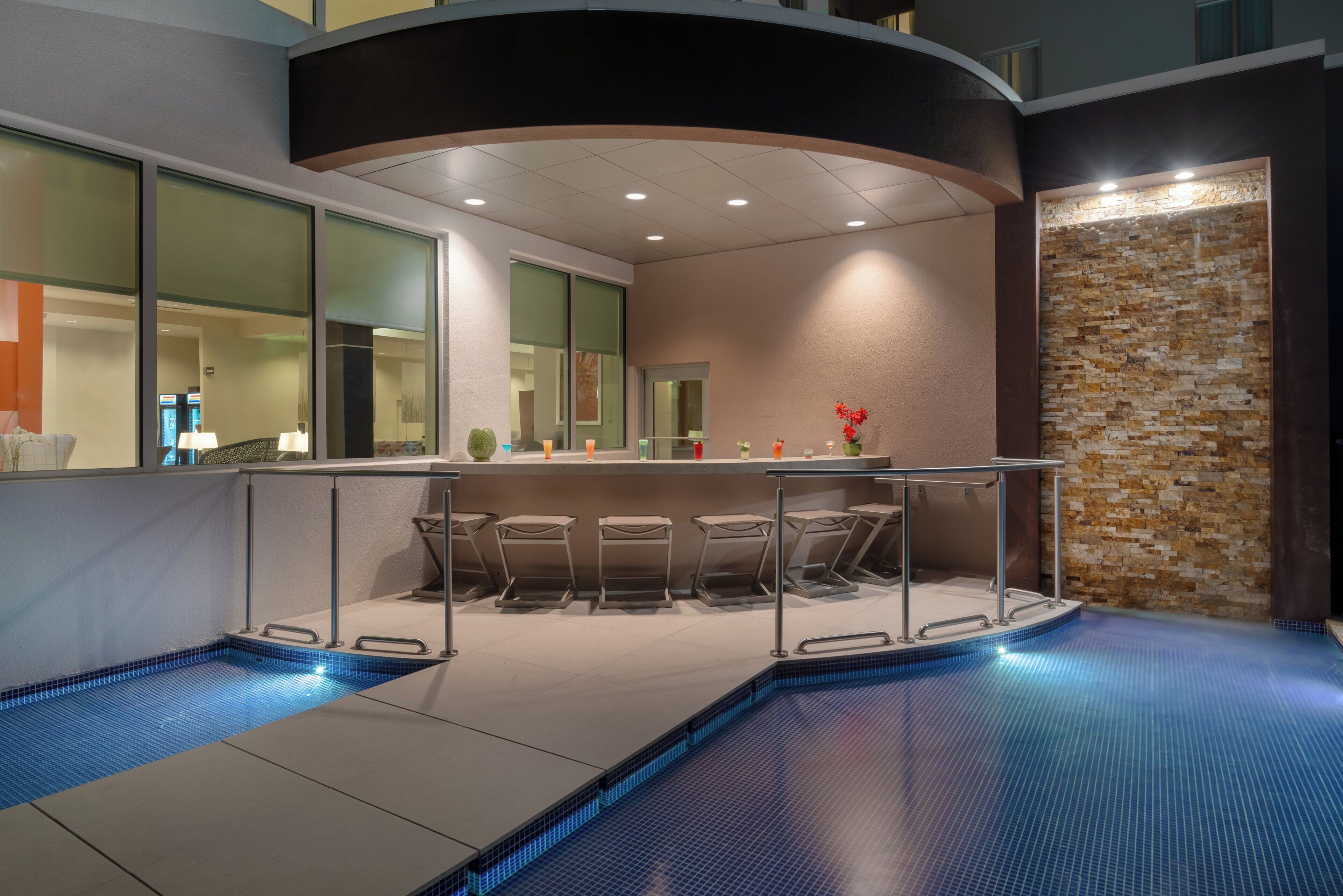 A modern indoor pool area with a bar and seating.