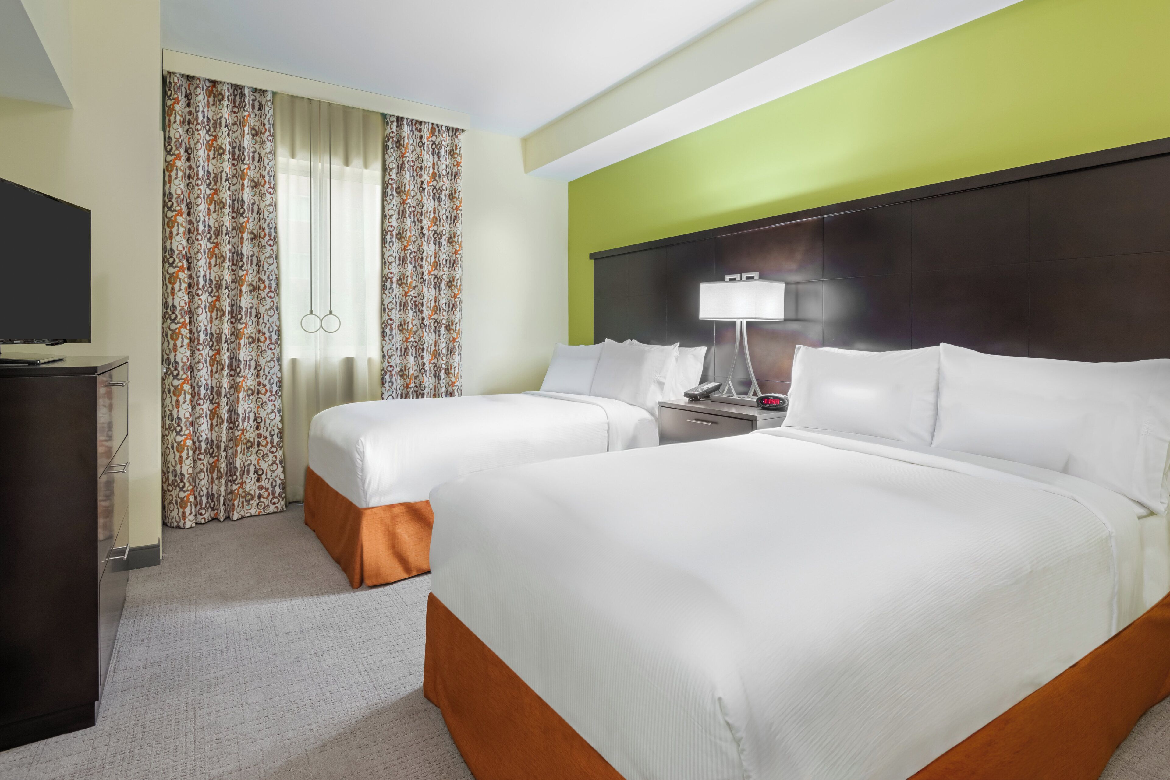 Een hotelkamer met twee bedden, een televisie, een bureau en een lamp.