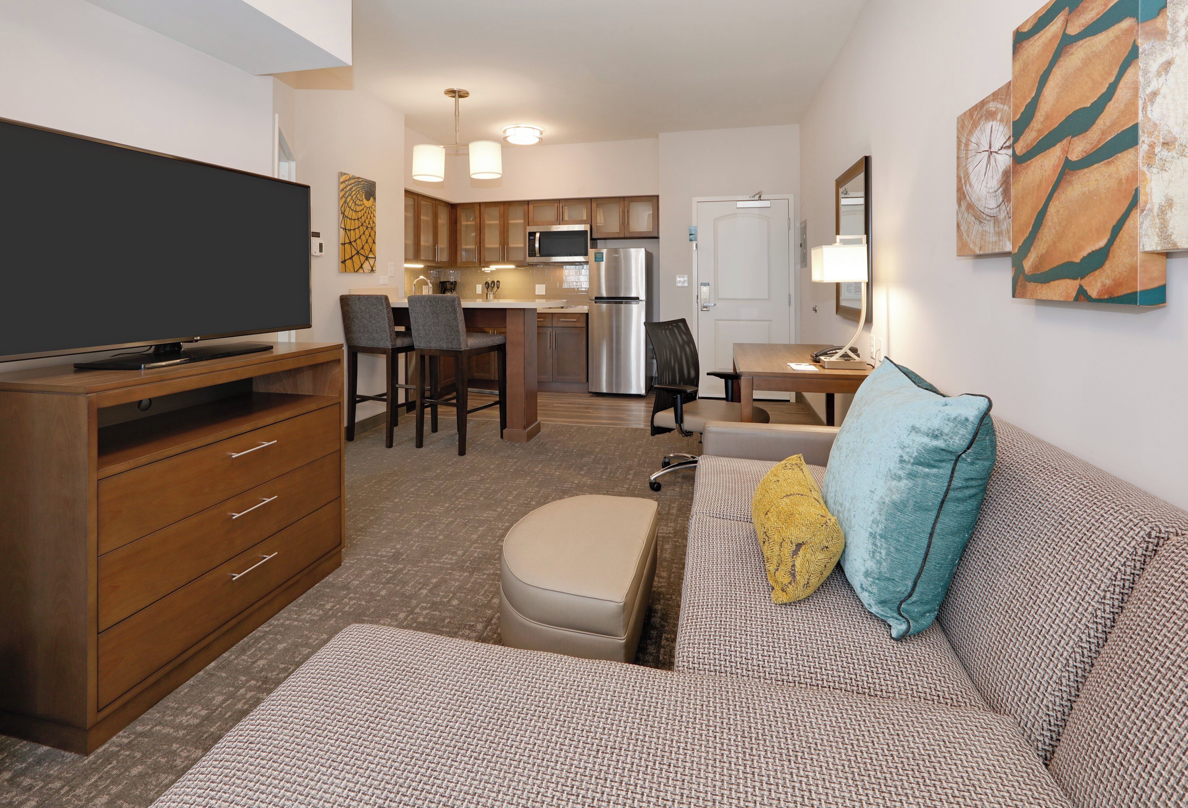 A compact living space with a kitchenette, a dining area, and a seating area with a sofa and ottoman.