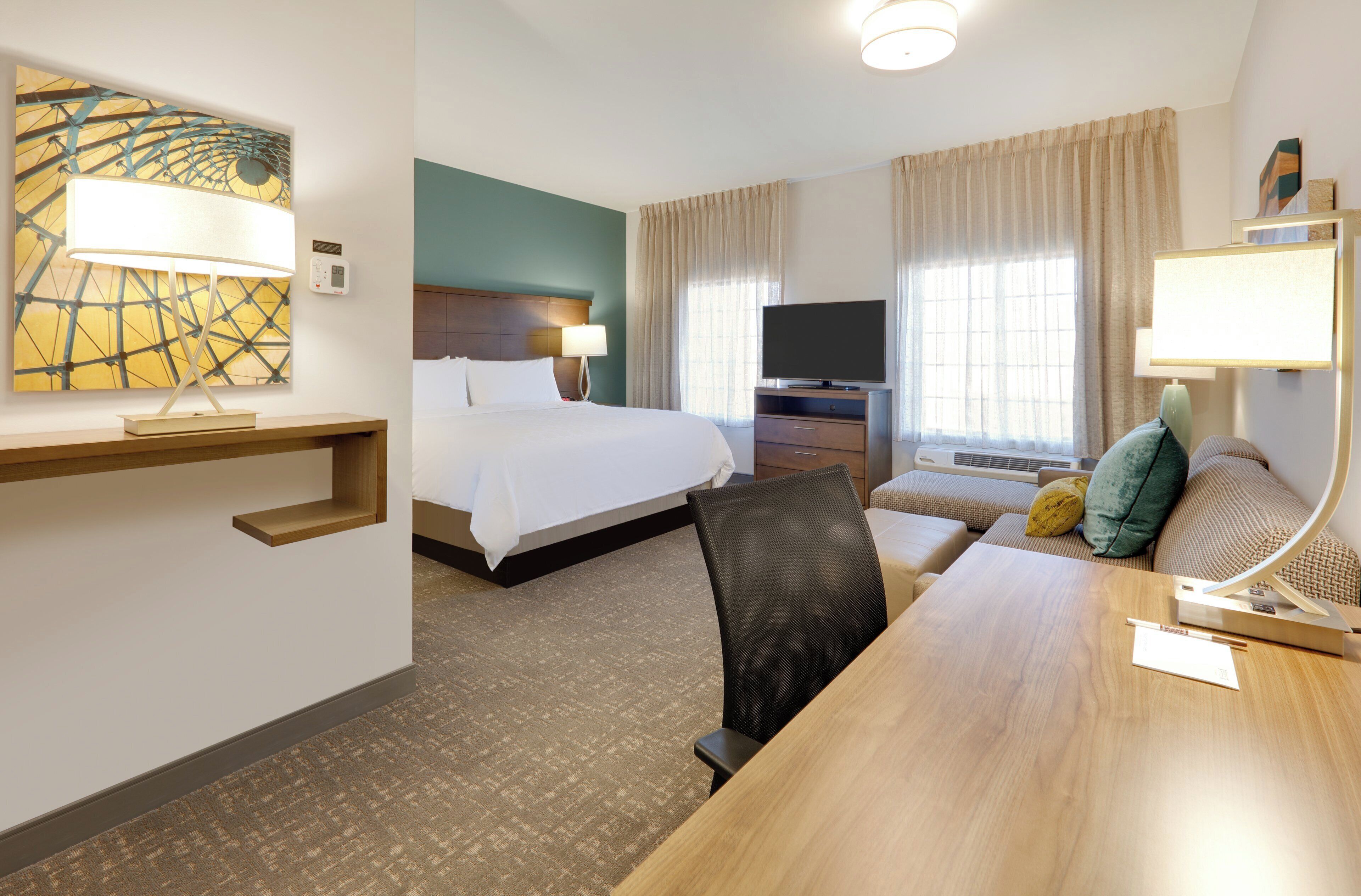 A hotel room with a bed, a desk, a TV, and a sofa.