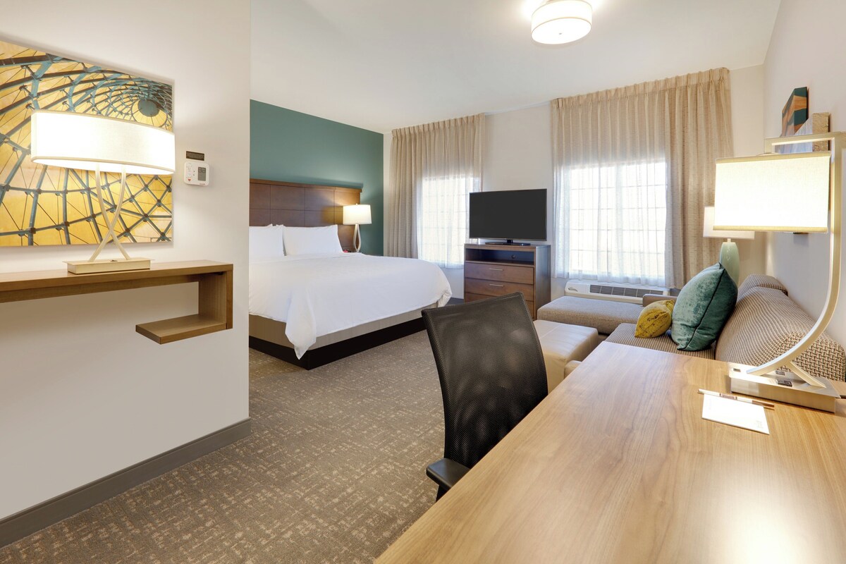 A hotel room with a bed, a desk, a TV, and a sofa.