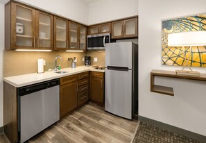 A modern kitchen with wooden cabinets, stainless steel appliances, and a tiled backsplash. - Staybridge Suites Oklahoma City Dwtn - Bricktown by IHG (Oklahoma City)