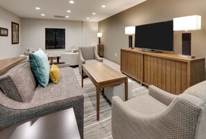 A modern living room with a sofa, armchairs, a coffee table, a TV, and a fireplace.