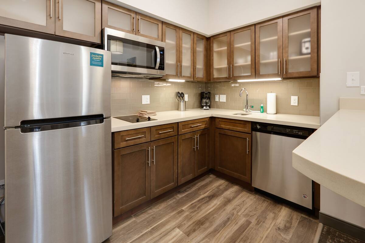A modern kitchen with stainless steel appliances, wooden cabinets, and a dishwasher.