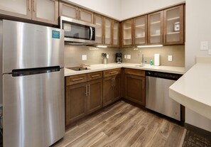 A modern kitchen with stainless steel appliances, wooden cabinets, and a dishwasher. - Staybridge Suites Oklahoma City Dwtn - Bricktown by IHG (Oklahoma City)