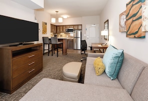 A compact living space with a flat-screen TV, wooden furniture, a kitchenette, and artwork on the walls. - Staybridge Suites Oklahoma City Dwtn - Bricktown by IHG (Oklahoma City)