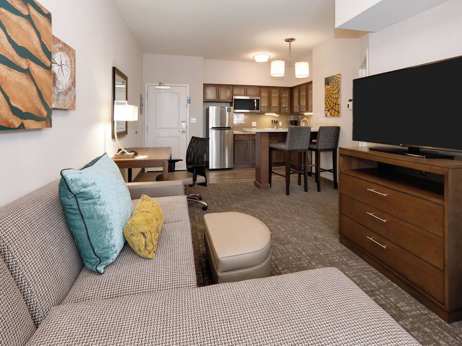 A compact living space with a kitchenette, a dining area, and a seating area with a sofa and ottoman.