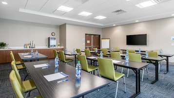 A conference room with multiple tables and chairs, equipped with water bottles and notepads.