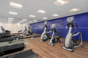 Un gimnasio con cintas de correr, bicicletas estáticas y máquinas elípticas.