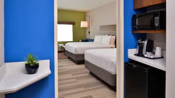 A hotel room with two beds, a microwave, a coffee maker, and a small plant on a shelf.