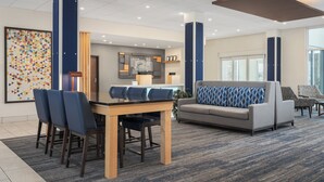 A modern hotel lobby with a dining area, seating, and a large window.