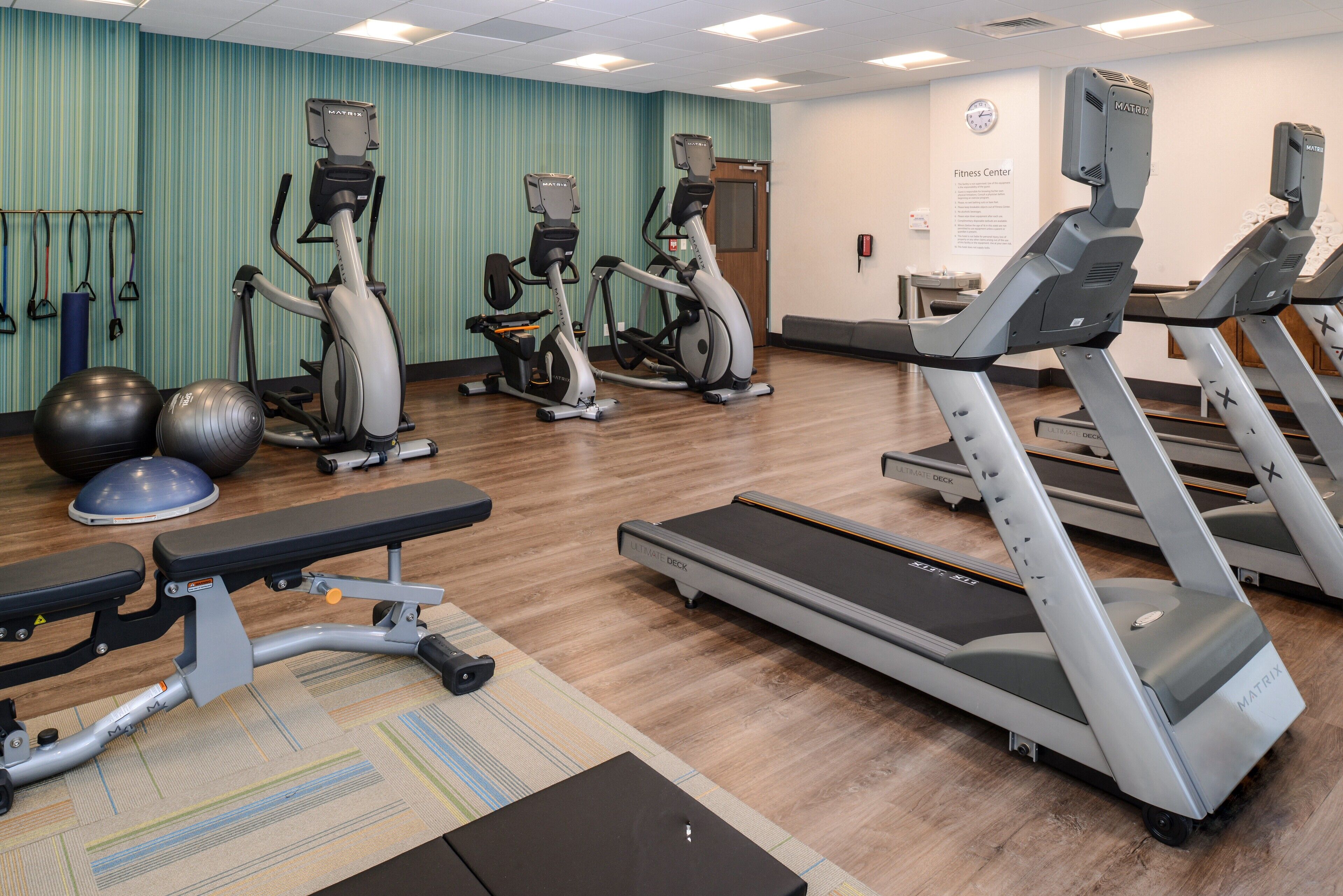 A fitness center with treadmills, elliptical machines, and exercise balls.