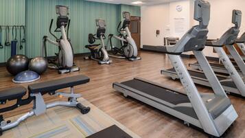 A fitness center with treadmills, elliptical machines, and exercise balls.